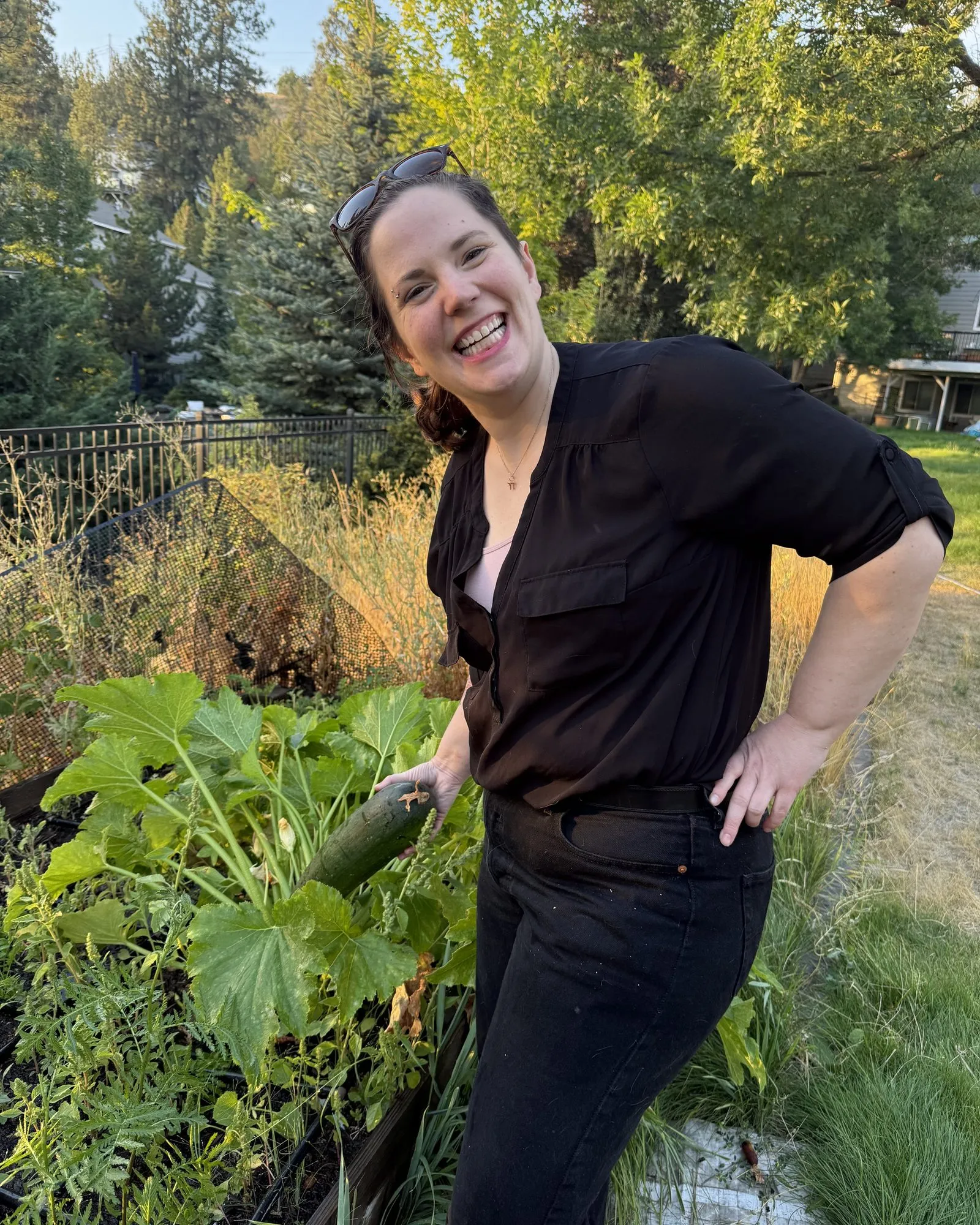 Dr. Oropeza holding a zucchini in a garden.