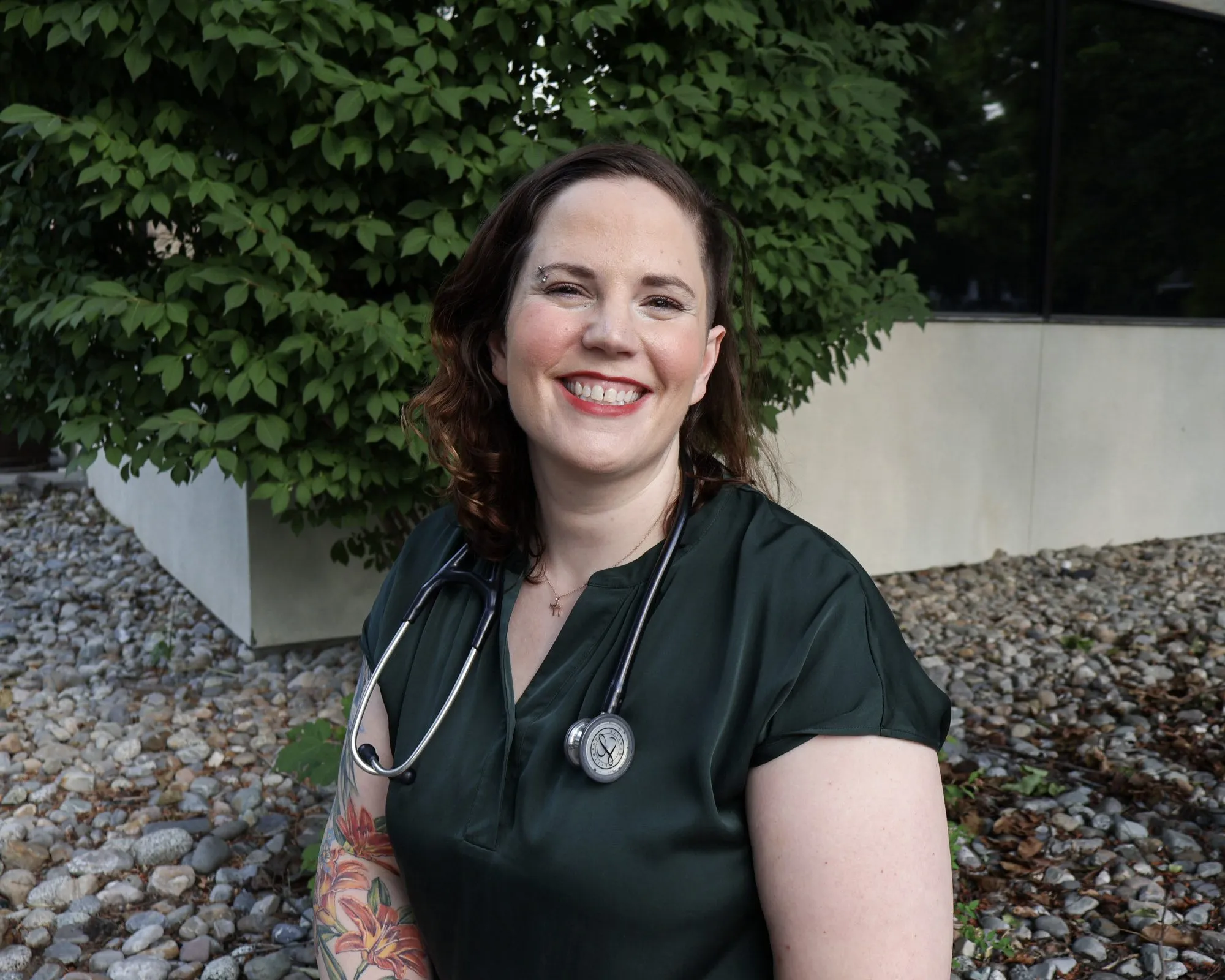 Dr. Amanda Oropeza outdoors in green scrubs and a stethoscope, smiling.